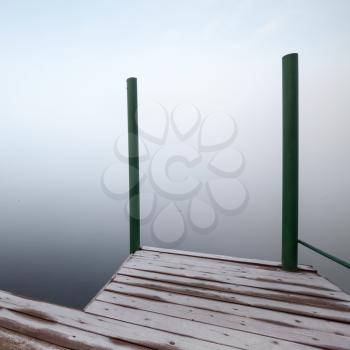 Foggy coastal abstract fragment with frozen wooden pier