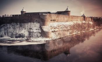 Ivangorod fortress at Narva river in winter season. Border between Russia and Estonia. Vintage stylized photo with tonal correction photo filter and vignette effect