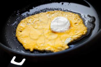 Original roasted eggs with white center and yellow base in black pan