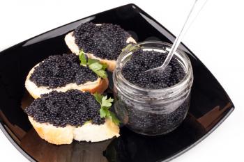 Small sandwiches with black caviar on dark plate