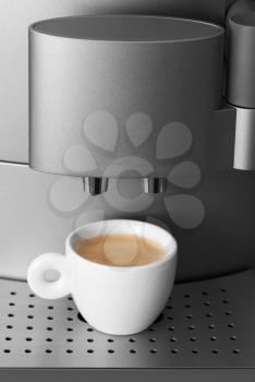 Small cup of espresso in modern automatic coffee machine