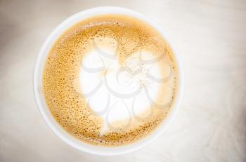 Cup of cappuccino coffee with heart shaped milk foam. Top view, selective focus