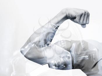 Double exposure abstract conceptual power photo collage, strong male hand showing  biceps and industrial mechanism background