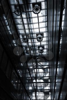 Dark abstract industrial interior with transparent ceiling, ventilation and spiral stairs