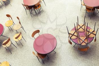 Round tables and chairs stand in empty cafe interior, top view, vintage toned photo