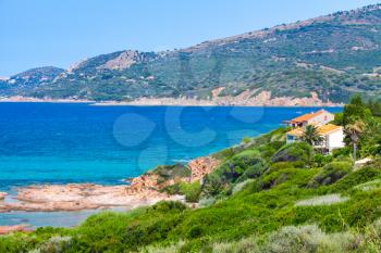 Summer coastal landscape of Corsica island. Small azure bay with lining house on rocky coast. Piana region, France