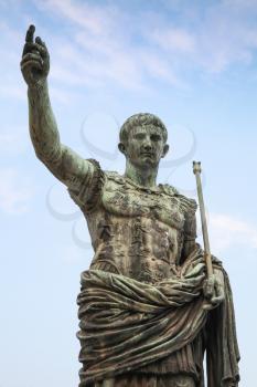 Ancient statue S.P.Q.R. IMP CAESAR Augustus PATRIAE PATER over cloudy sky. Via dei Fori Imperiali street, Rome, Italy