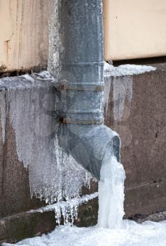 Winter city fragment. Icicles and frost on drainpipe