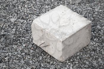Big concrete construction block with metal lug on gray gravel