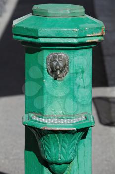 Old green street drinking fountain with clear water decorated with lion head. Helsinki, Finland