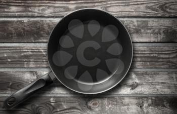 Empty black frying pan on old dark gray wooden table background