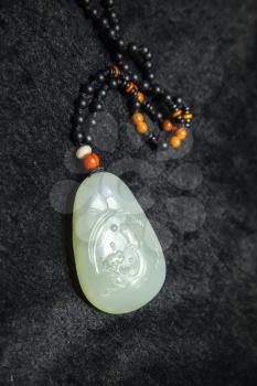 Hangzhou, China - December 2, 2014: Traditional Chinese stone amulet made of jade with art carving lays on black counter in gemstones shop