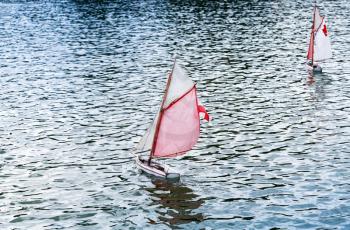 Traditional small wooden sailing toy boats in the pond of park Jardin du Luxembourg, Paris, France