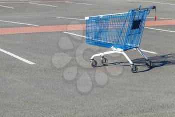 Empty shopping cart stands on a parking near supermarket