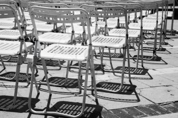 Rows of empty white metal chairs in an open air concert hall