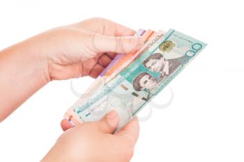 Dominican Republic money in female hands with blurred effect on fingers, closeup studio photo isolated on white background