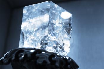 Blue toned photo of natural transparent quartz crystal in cube shape, selective focus