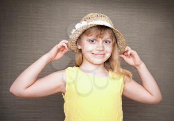 Portrait of a smiling little blond girl with straw hat