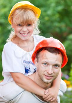 Portrait of smiling young man and his little daughter as a construction workers family