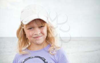 Portrait of a slightly smiling little blond beautiful Russian girl on the sea coast