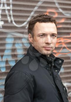Portrait of young Caucasian man in black with graffiti on a background
