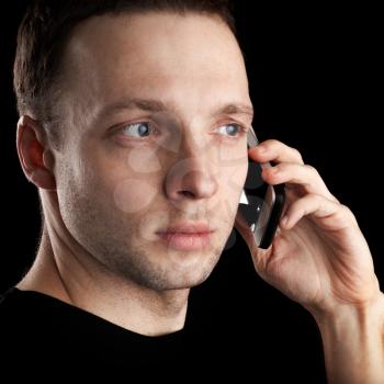 Young Caucasian man talks on mobile phone. Closeup portrait  isolated on black background