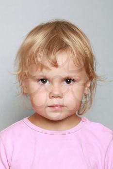 Caucasian baby girl closeup portrait. Headshot on gray