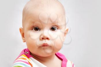 Little calm brown eyed Caucasian baby closeup studio portrait on gray background