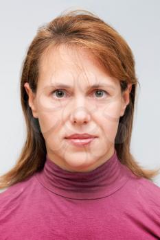 Closeup studio face portrait of young Caucasian ordinary woman isolated on gray background