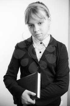 Black and white portrait of blond Caucasian schoolgirl with textbook