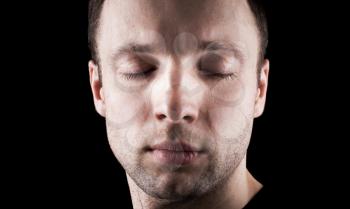 Young Caucasian man's portrait with closed eyes above black background