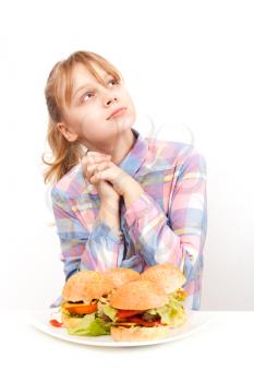 Little blond girl with big homemade hamburgers on white plate