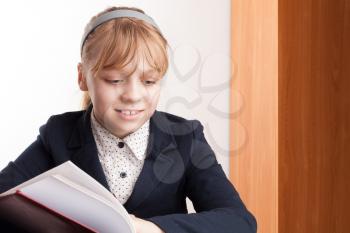 Closeup portrait of smiling blond Caucasian schoolgirl reading textbook