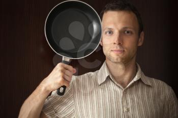 Young man portrait with black frying pan