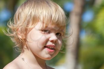 Outdoor closeup portrait of cute smiling Caucasian blond baby girl