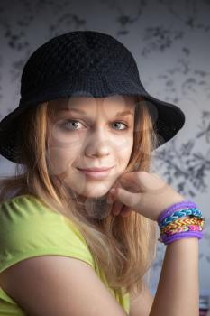 Portrait of beautiful blond teenage girl in black hat and rubber loom bracelets