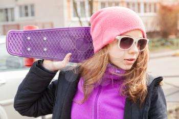 Blond beautiful teenage girl in sunglasses with skateboard, outdoor urban portrait