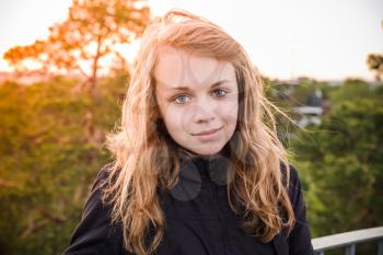 Outdoor closeup portrait of teenage Caucasian blond girl with bright evening sunlight back light