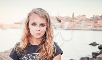 Outdoor portrait of blond Caucasian teenage girl standing on a seacoast, Gaeta, Italy