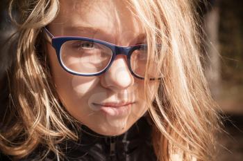 Beautiful blond Caucasian teenage girl in glasses, outdoor close-up portrait