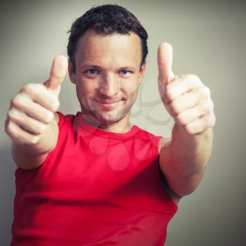 Positive young smiling man shows thumbs up, square photo with vintage tonal correction filter effect