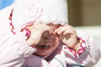 Little baby girl in pink clothes crying, closeup outdoor portrait