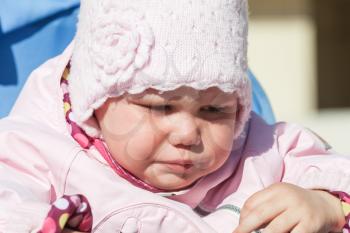Little baby girl in pink crying, closeup outdoor portrait