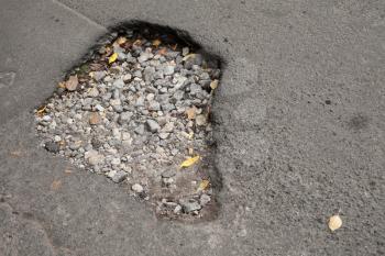 Pothole with gravel on damaged urban asphalt road