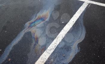 Oil spill on dark asphalt, parking lot with dividing lines