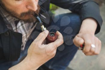 Bearded man smoking pipe, outdoor photo with selective focus