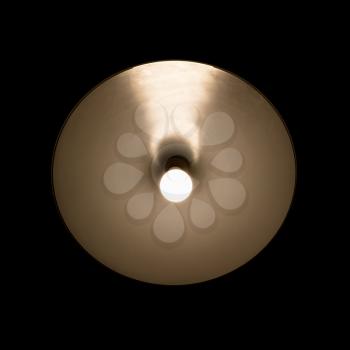 Tungsten lamp glowing in the round metallic lampshade isolate over black background