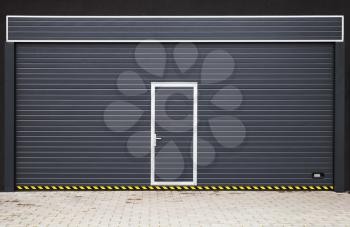 Dark gray modern garage gate with small door in the middle, background photo texture