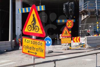 Warning roadsigns along urban road. Swedish text means intersecting bicycling