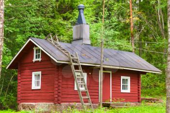 Traditional Scandinavian red wooden house on green forest background. Kotka, Finland